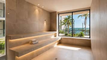 Un baño moderno con un ventanal grande, un banco integrado y vistas al mar.