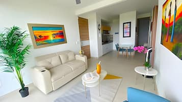 Un salon moderne avec un canapé beige, un fauteuil bleu, une table basse et un coin repas comprenant une table et des chaises.