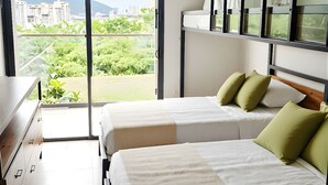 Habitación de hotel con dos camas, un tocador, una ventana con vista a la ciudad y un ventilador de techo.