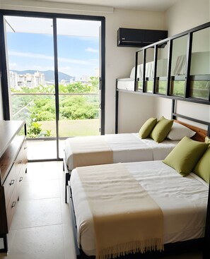 Een hotelkamer met twee bedden, een dressoir, een raam met uitzicht op de stad en een plafondventilator.