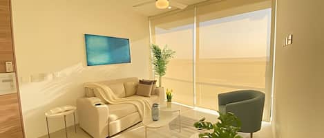 Una sala de estar moderna con un sofá, una mesa de centro y un sillón, un ventanal con vistas y un ventilador de techo.