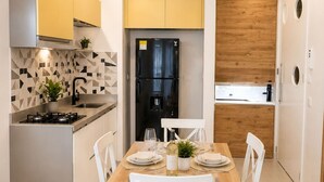 Una cocina moderna con estufa empotrada, un refrigerador negro y un comedor con una mesa de madera dispuesta para dos personas.
