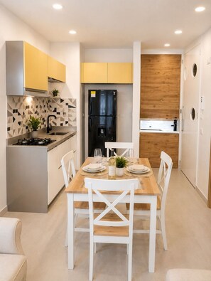 Een moderne keuken met een ingebouwde kookplaat, een zwarte koelkast en een eethoek met een houten tafel gedekt voor twee personen.