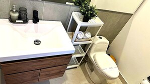 Een badkamer met een wit wastafel, houten wastafelmeubel en een toilet.