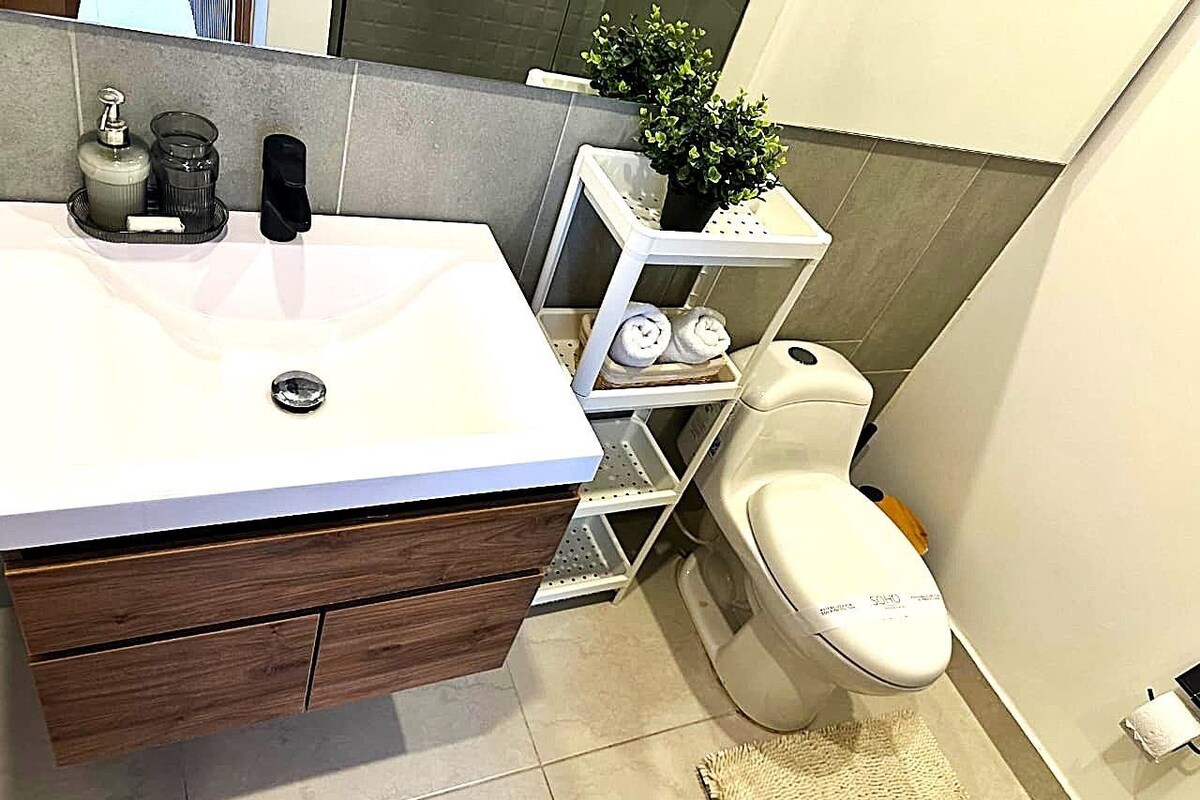 A bathroom with a white sink, wooden vanity, and a toilet.