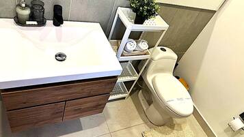 Une salle de bain avec un lavabo blanc, un meuble-lavabo en bois et des toilettes.