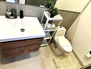 A bathroom with a white sink, wooden vanity, and a toilet.