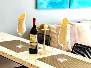A dining table with a bottle of wine, two glasses, and a candle. - Apartamentos Salinas del Mar - by SOHO (Santa Marta)