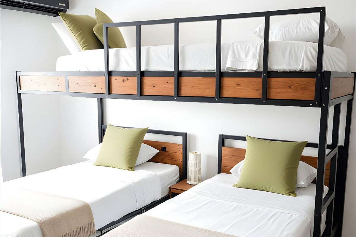 A bunk bed room with two beds, a bedside table, and a wall-mounted air conditioner.