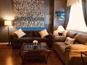 Relax in this stylish living room with a comfortable sofa, abstract art, and a glass coffee table.