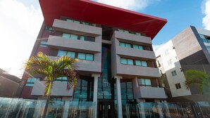 Un edificio moderno di un hotel con un’aggettura rossa, diversi piani e ampie finestre.