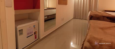 A hotel room with a bed, a television mounted on the wall, a wardrobe, and a mirror reflecting the room.