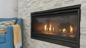 A modern living room with a stone wall and a fireplace.