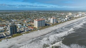 A coastal cityscape with high-rise buildings, a sandy beach, and ocean waves.