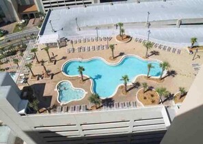 Piscina com design singular, rodeada por palmeiras e espreguiçadeiras.