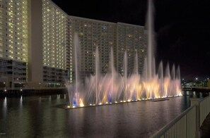 Un hotel con varios pisos, una fuente ornamental y un muelle.