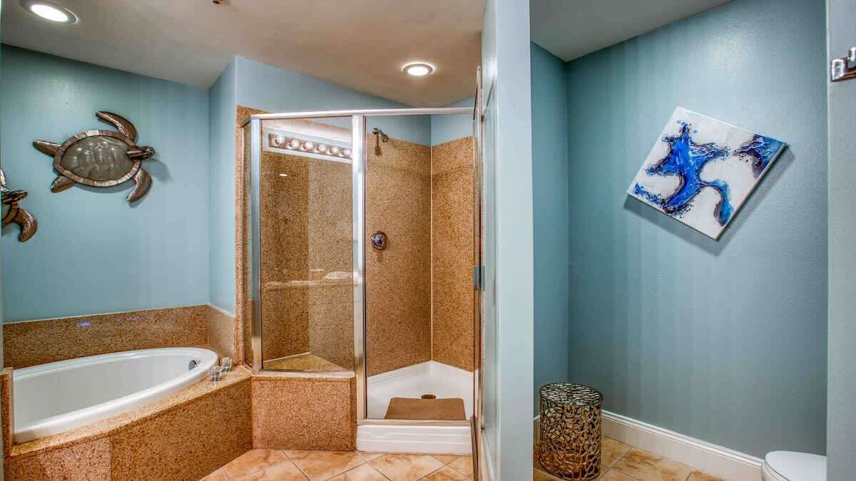 A bathroom with a glass-enclosed shower, a bathtub, and a toilet.