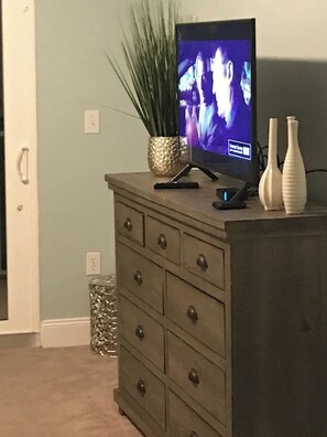 Ein Fernseher auf einer Holzkommode mit Schubladen, eine Zierpflanze und zwei Vasen.