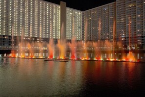 Ein Hotel mit mehreren Hochhäusern, einer Wasserspielen-Anlage und einer gut beleuchteten Fassade.