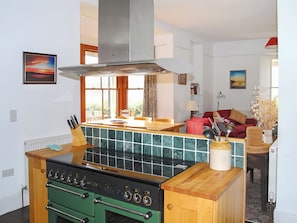 Una cocina con estufa, horno y comedor con mesa y sillas.