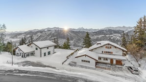A snow-covered mountain house with a garage and a driveway. - Crans Montana Suites (Crans-Montana)