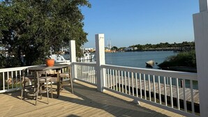 A wooden deck with a white railing, overlooking a marina with boats and a clear view of the water. - Ultimate Fishing Retreat: Spacious 3BR Bolivar Island Home with Dock & Cleaning Stations - Sleeps 12! (Bolivar Peninsula)