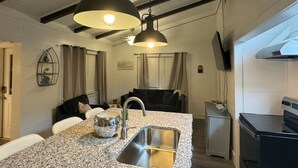A compact kitchen with a granite countertop, stainless steel sink, and two pendant lights. - Ultimate Fishing Retreat: Spacious 3BR Bolivar Island Home with Dock & Cleaning Stations - Sleeps 12! (Bolivar Peninsula)
