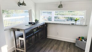A kitchen with a bar area, white walls, and a wooden floor. - Ultimate Fishing Retreat: Spacious 3BR Bolivar Island Home with Dock & Cleaning Stations - Sleeps 12! (Bolivar Peninsula)