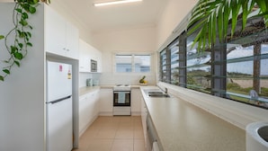A modern kitchen with white cabinetry, a stainless steel sink, a microwave, and a stove.