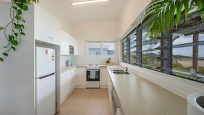 Una cocina moderna con armarios blancos, un lavamanos de acero inoxidable, un microondas y una estufa.
