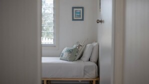 A room with a bed, a window, and a framed picture on the wall.