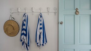 A wall-mounted towel rack with a straw hat and striped towels.
