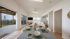 A spacious dining area with a table set for a meal, a ceiling fan, and a view of the outdoors. - Driftaway- Absolute Beach Front- Stone Real Estate Yamba (Brooms Head)
