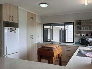 A modern kitchen with a built-in oven, a wooden table, and a window with a view of the outside.