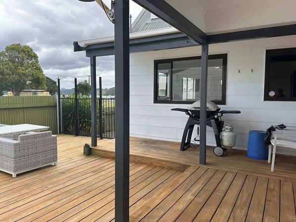 A covered outdoor deck with a table and chairs, a scooter, and a gas cylinder.