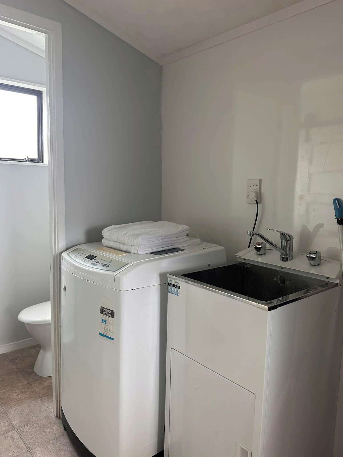 A compact laundry room with a washing machine, a dryer, and a sink.