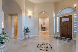 Ein geräumiges Foyer mit Holztür, einer Rezeption und einem dekorativen Teppich.