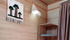 Una habitación de hotel con una cama, una lámpara colgante, un armario y una obra de arte en la pared.