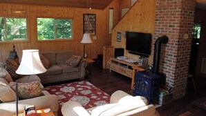 A cozy living room with a fireplace, wooden walls, a sofa, and a television.
