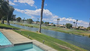 Ein Schwimmbad mit Blick auf einen Golfplatz und ein Gewässer.