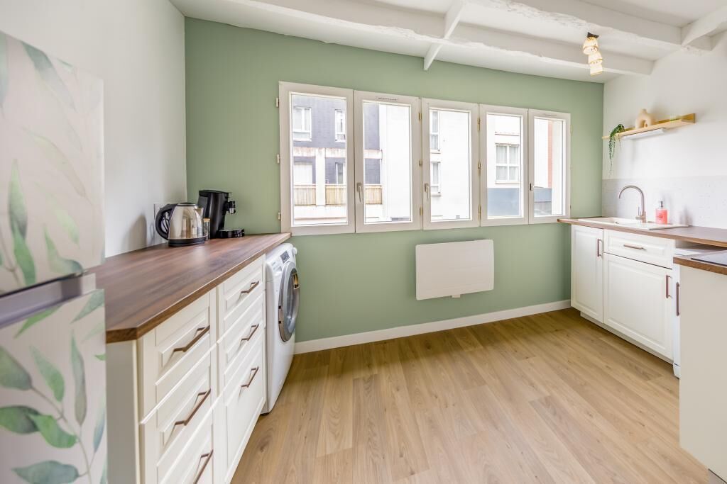 A kitchen with a washing machine, a coffee maker, and a radiator.