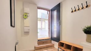 A hallway with wooden flooring, a bench, a coat rack, and a door leading outside.