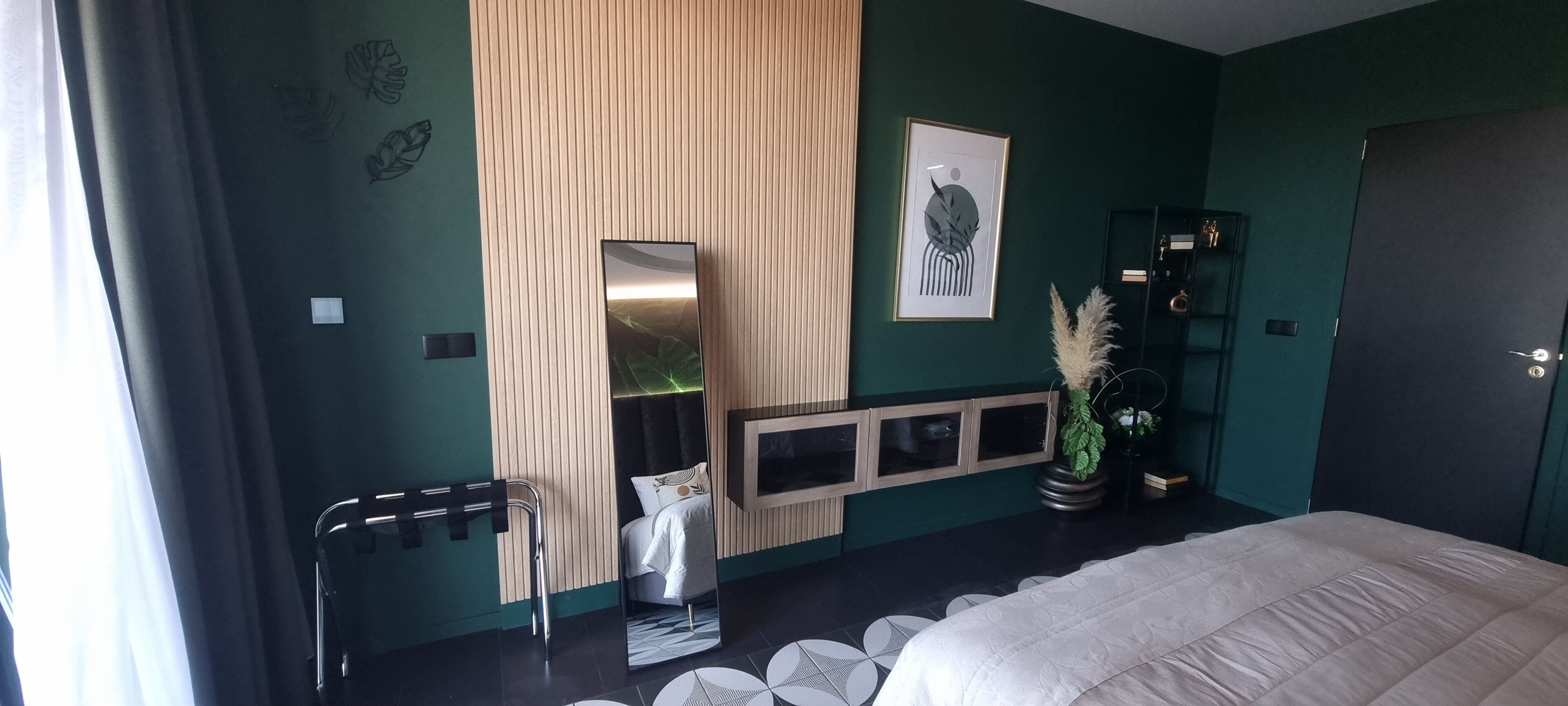 Ein modernes Schlafzimmer mit Bett, Spiegel, Kommode und Pflanze.