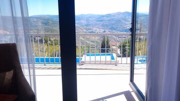 A balcony with a view of a mountainous landscape and a swimming pool.
