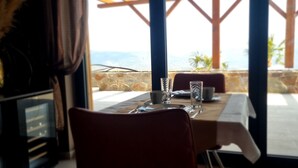 Un tavolo da pranzo apparecchiato con posate e bicchieri, con vista panoramica su un muro in pietra e palme.