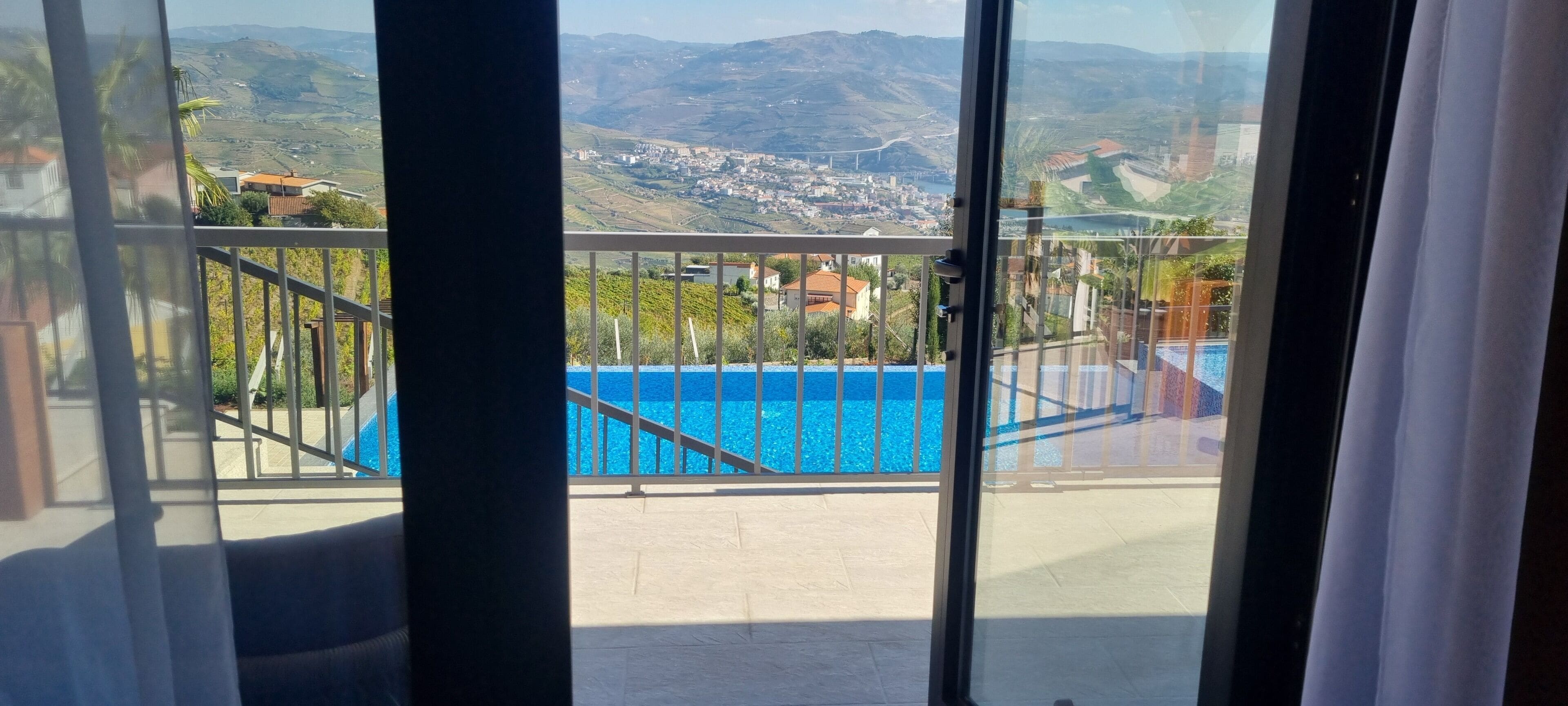 Ein Balkon mit Blick auf einen Pool und eine entfernte Landschaft.