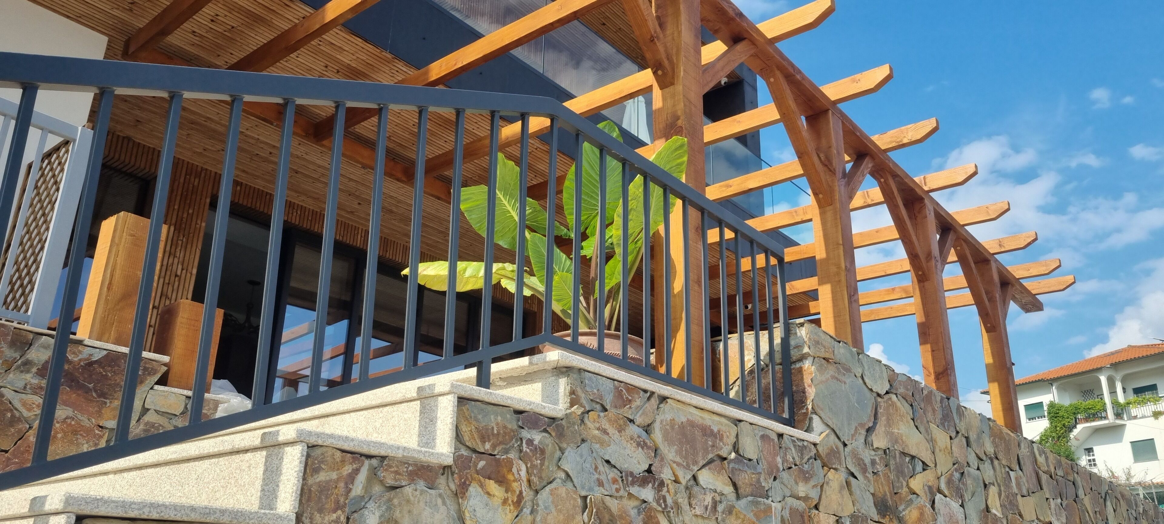 A stone staircase leading up to a wooden pergola with a metal railing.