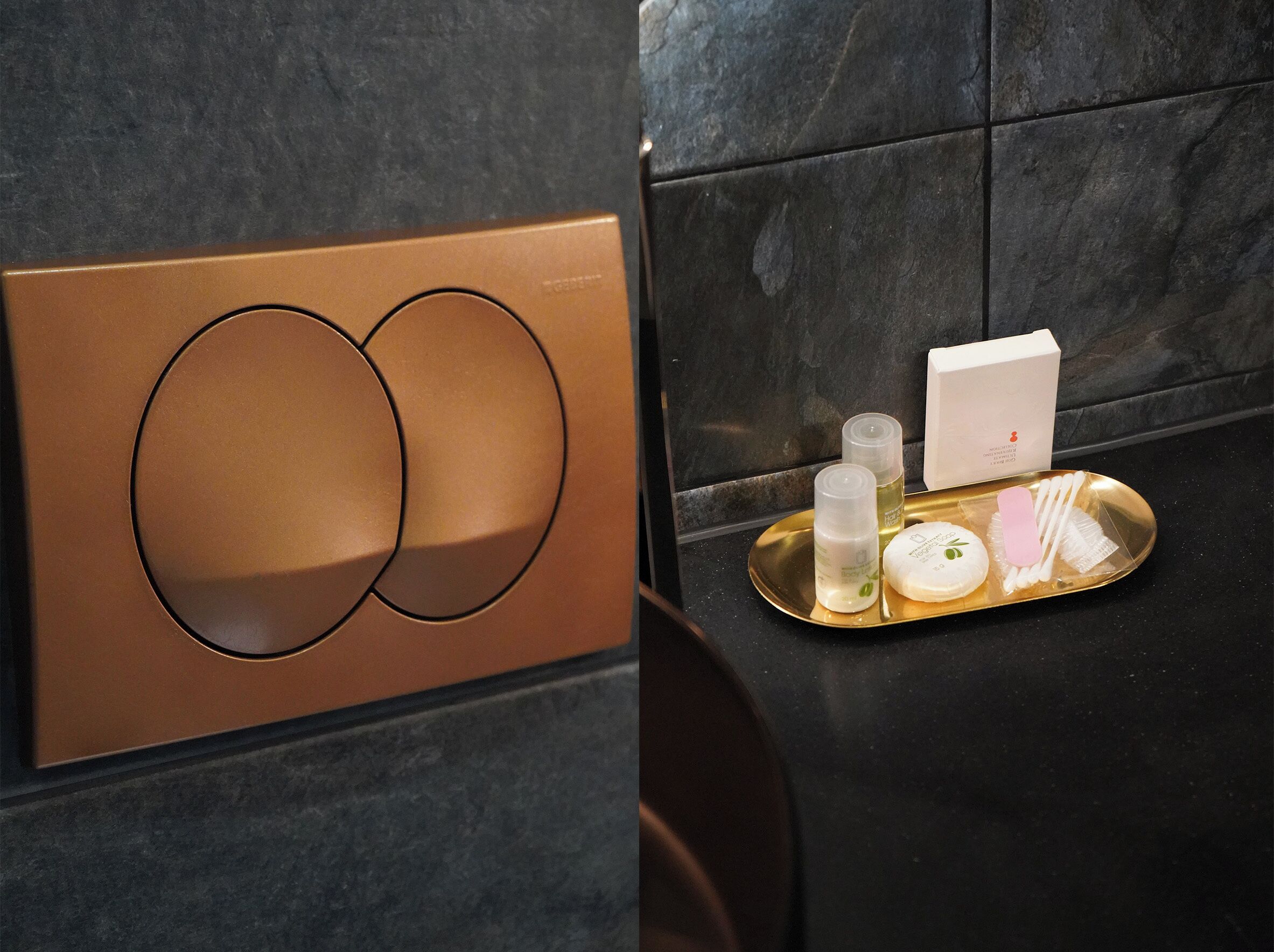 A bathroom with a modern design, featuring a metallic panel and a tray with toiletries.
