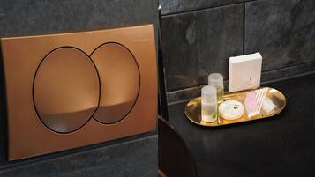 A bathroom with a modern design, featuring a metallic panel and a tray with toiletries.