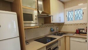 Cocina compacta con horno integrado, microondas y lavavajillas.